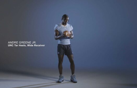 Andre Greene Jr stands with a football