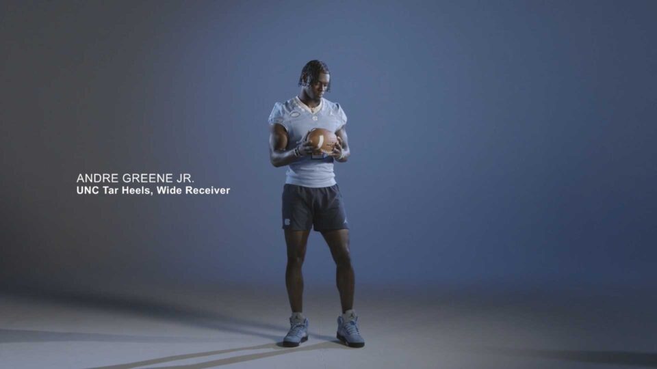 Andre Greene Jr stands with a football